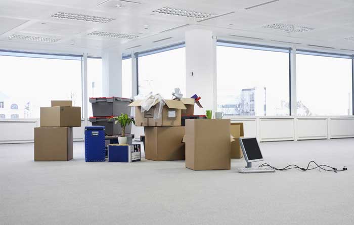 Office furniture packed in middle of empty room.